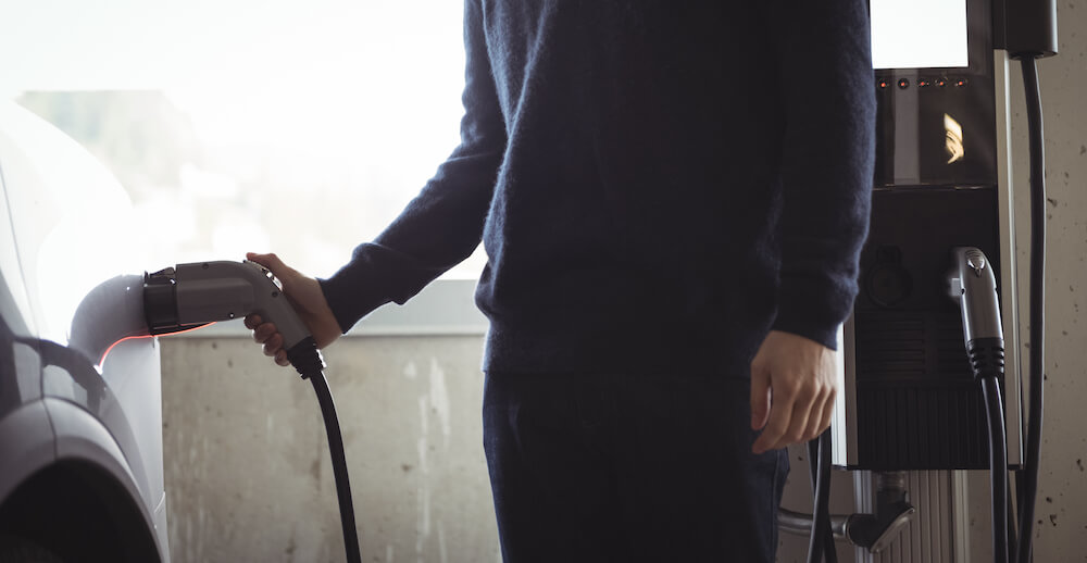 homme recharge sa voiture dans le parking d'une copropriété