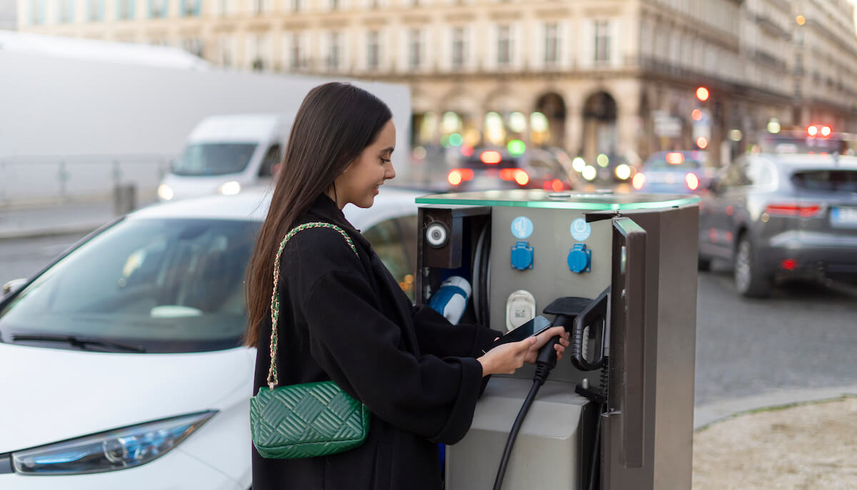 femme qui utilise une borne de recharge publique