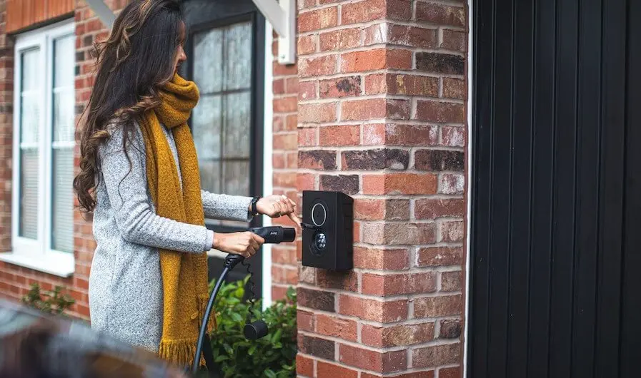 femme qui utilise sa borne de recharge électrique chez elle